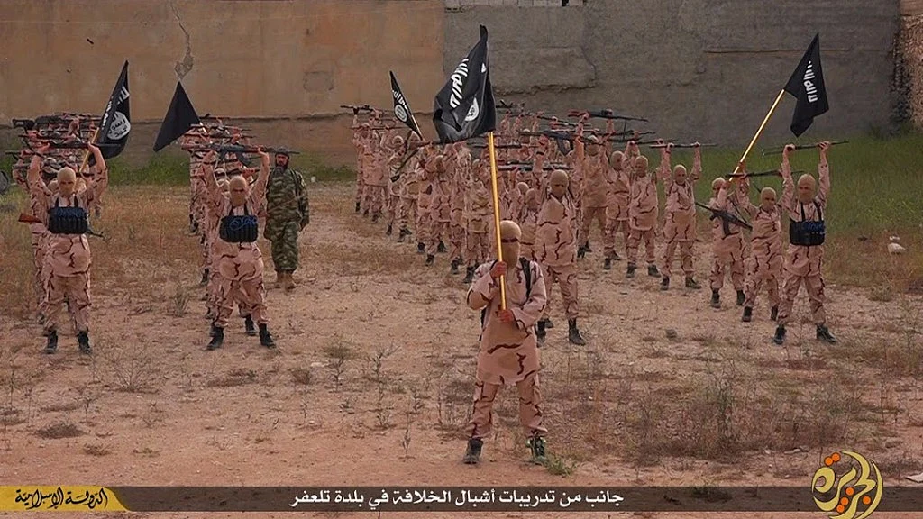 In this file photo released on 25 April 2015, by a militant website, young boys known as the “lion cubs” hold rifles and Islamic State group flags as they exercise at a training camp in Tal Afar, near Mosul, northern Iraq. (Photo: AP)