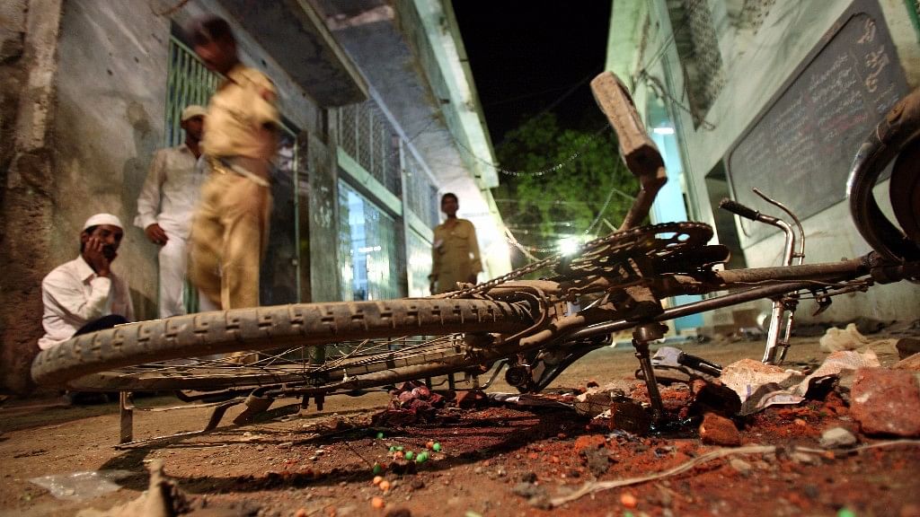 People walk past a damaged bicycle lying at a blast site inside a mosque in Malegaon, 260 km northeast of Mumbai on 9 September. (Photo: Reuters)