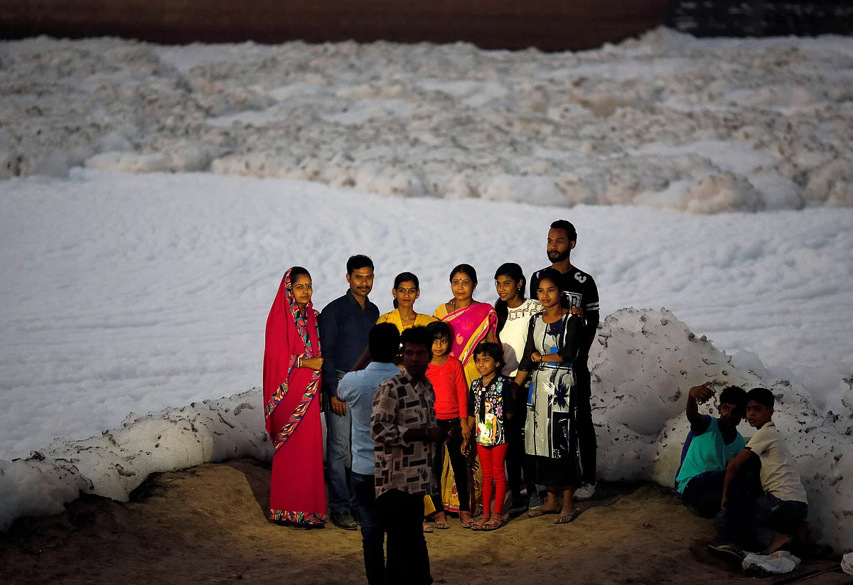A family gets its picture taken in front of the foam covering the polluted Yamuna in New Delhi. (Photo: Reuters/Adnan Abidi)