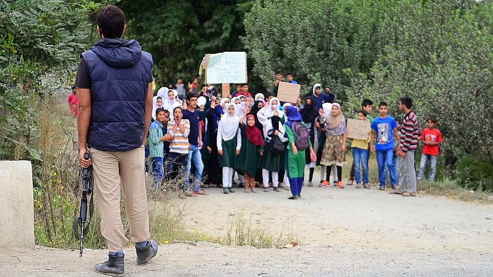 Children protesting against the government on the outskirts of Srinagar as a Jammu and Kashmir Police official looks on. Most schools and colleges have been shut in the Valley since the agitation began in July. (Photo: Jaskirat Singh Bawa)