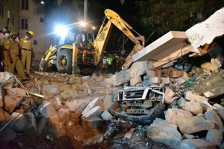 A car stuck under piles of collapsed building debris. (Photo Courtesy: <i>The News Minute</i>)