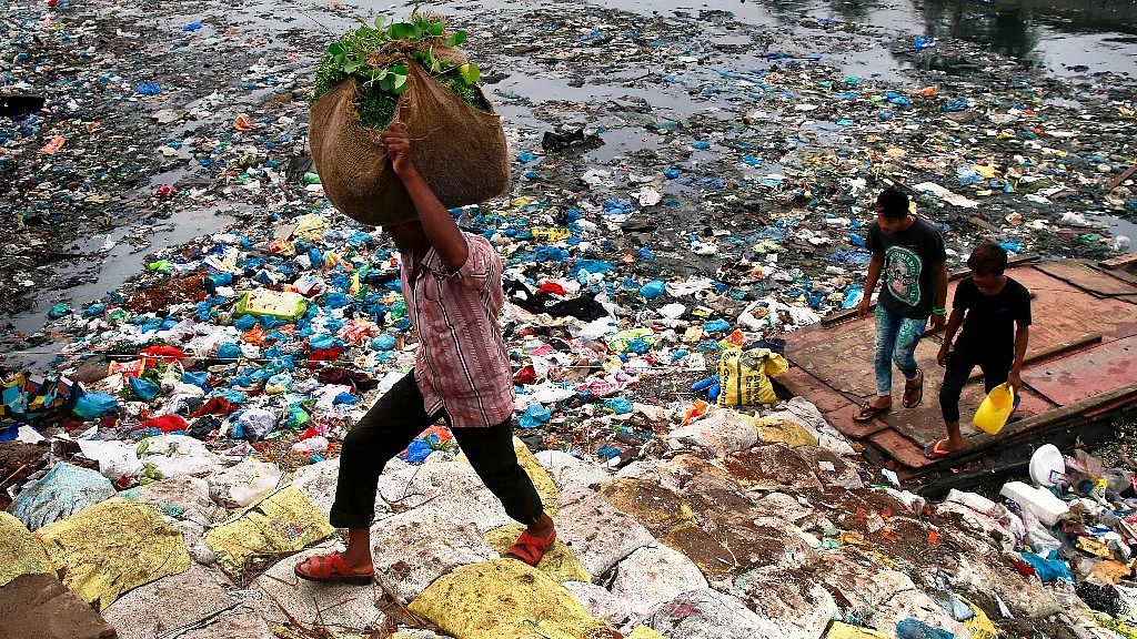 A man walks past a polluted canal littered with plastic bags in Mumbai, 2 October, 2016. India accounts for about 4.5 percent of global greenhouse gas emissions. (Photo:AP)