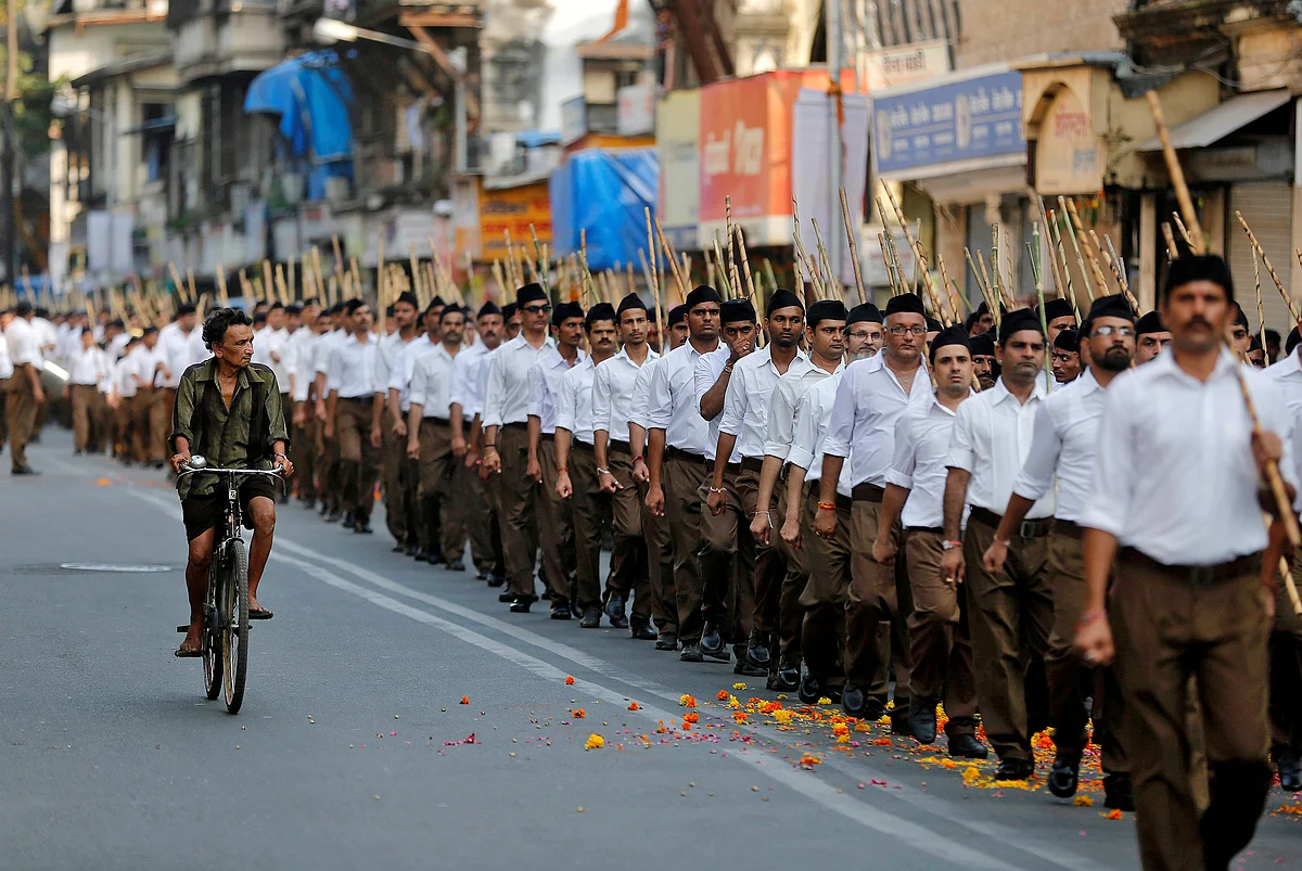 A man rides his bicycle past volunteers of the Rashtriya Swayamsevak Sangh (RSS) taking part in a march during celebrations to mark Vijaya Dashmi in Mumbai. (Reuters/Shailesh Andrade)
