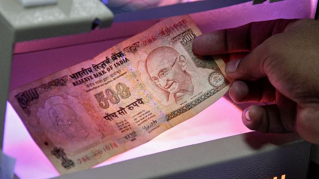 

An employee uses an electronic machine to check an Indian currency note. (Photo: Reuters)