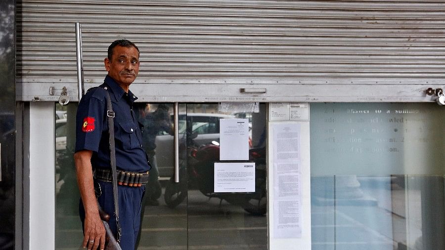 Representational image of a security guard standing before a half-shut bank. (Picture: Reuters)