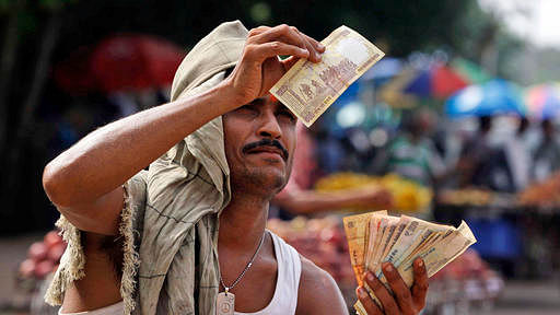 File photo of a roadside fruit vendor checks the authenticity of a 500 rupee note received from a customer in the eastern Indian city of Bhubaneswar, India. (Photo: AP)