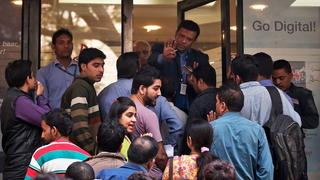 A bank official asks people to wait patiently in queues outside a bank in New Delhi. (Photo: AP)  