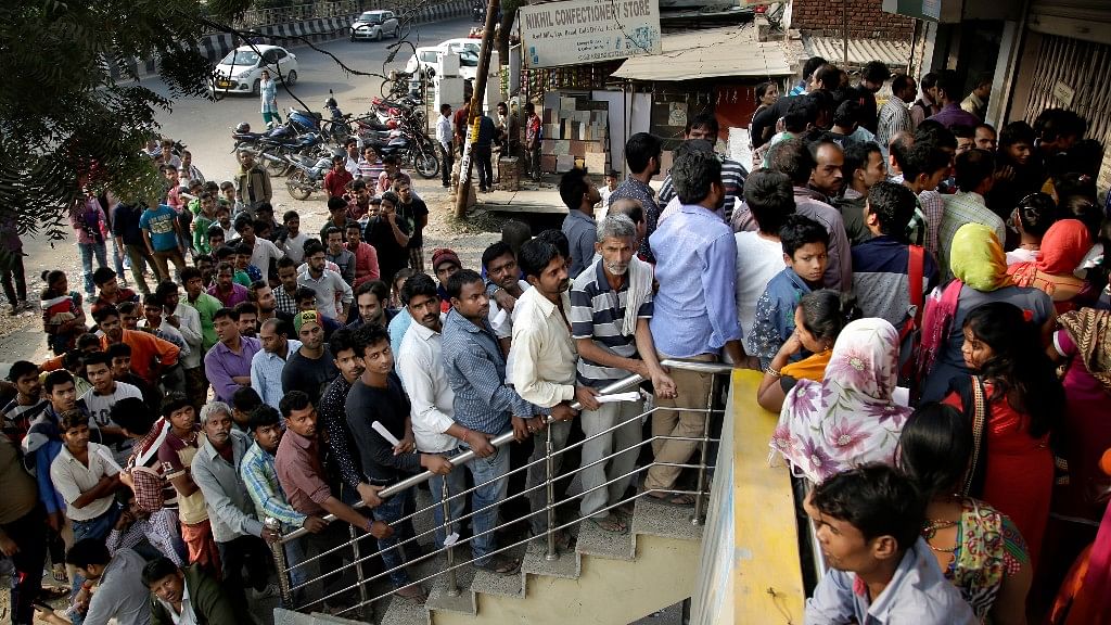 People stand in a queue to deposit and exchange discontinued currency notes outside a bank on the outskirts of New Delhi. (Photo: AP)