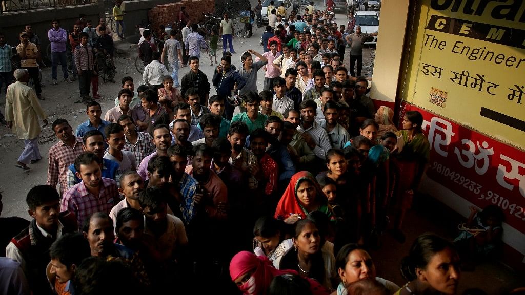 People stand in a queue to deposit and exchange discontinued currency notes, outside a bank on the outskirts of New Delhi. (Photo: AP)