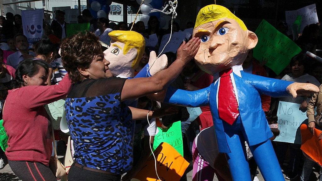 

Women smack pinatas at the likeness of US President Donald Trump in Mexico City,  20 January 2017. (Photo: AP)