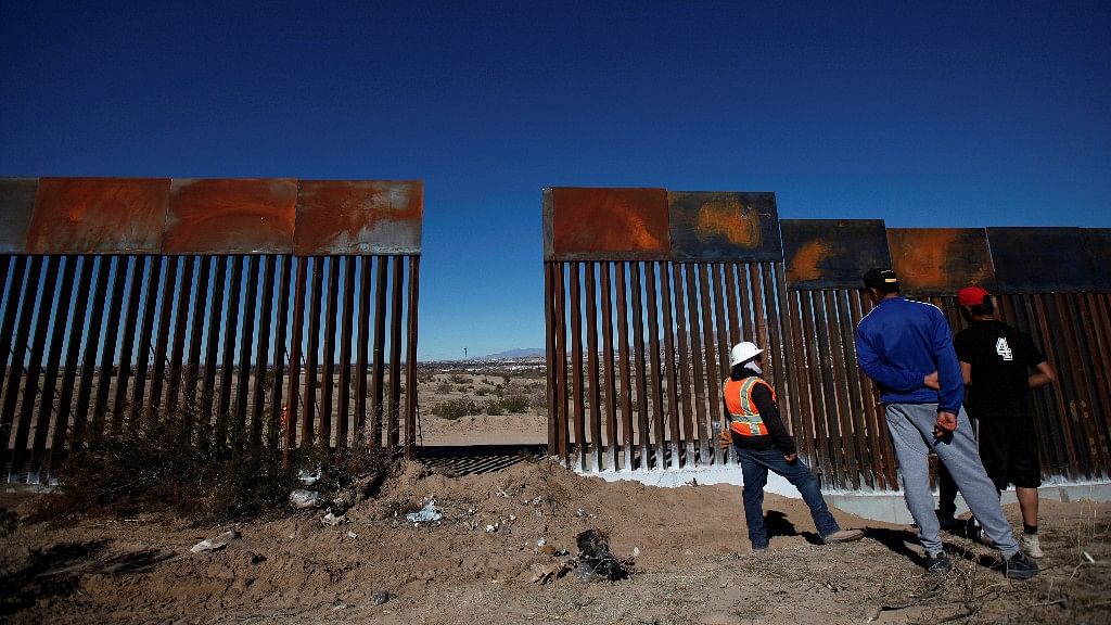 A worker chats with residents at a newly built section of the US-Mexico border fence at Sunland Park.&nbsp;