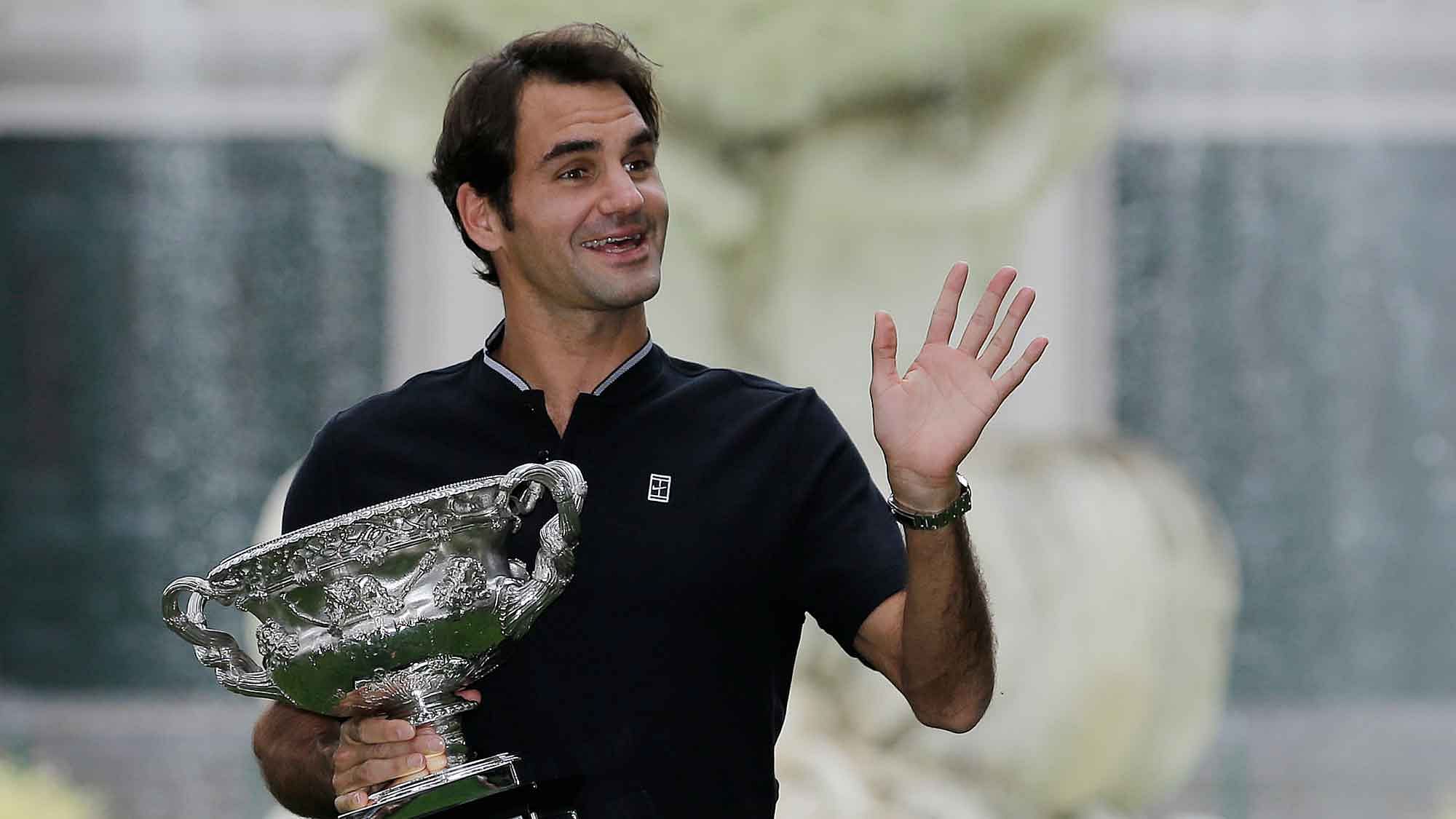 Switzerland’s Roger Federer waves to fans as he holds his Australian Open trophy at Carlton Gardens in Melbourne, Australia. (Photo: AP)