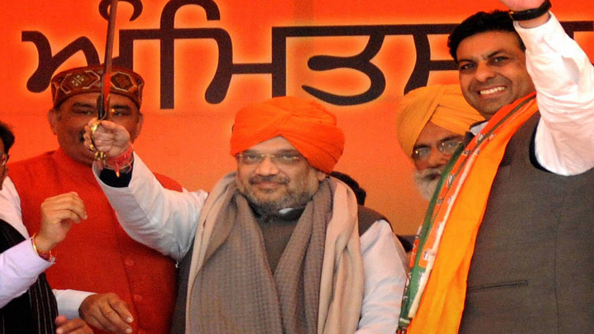 Amit Shah holds out a ceremonial sword at a rally in Amritsar on Monday. (Photo: PTI)