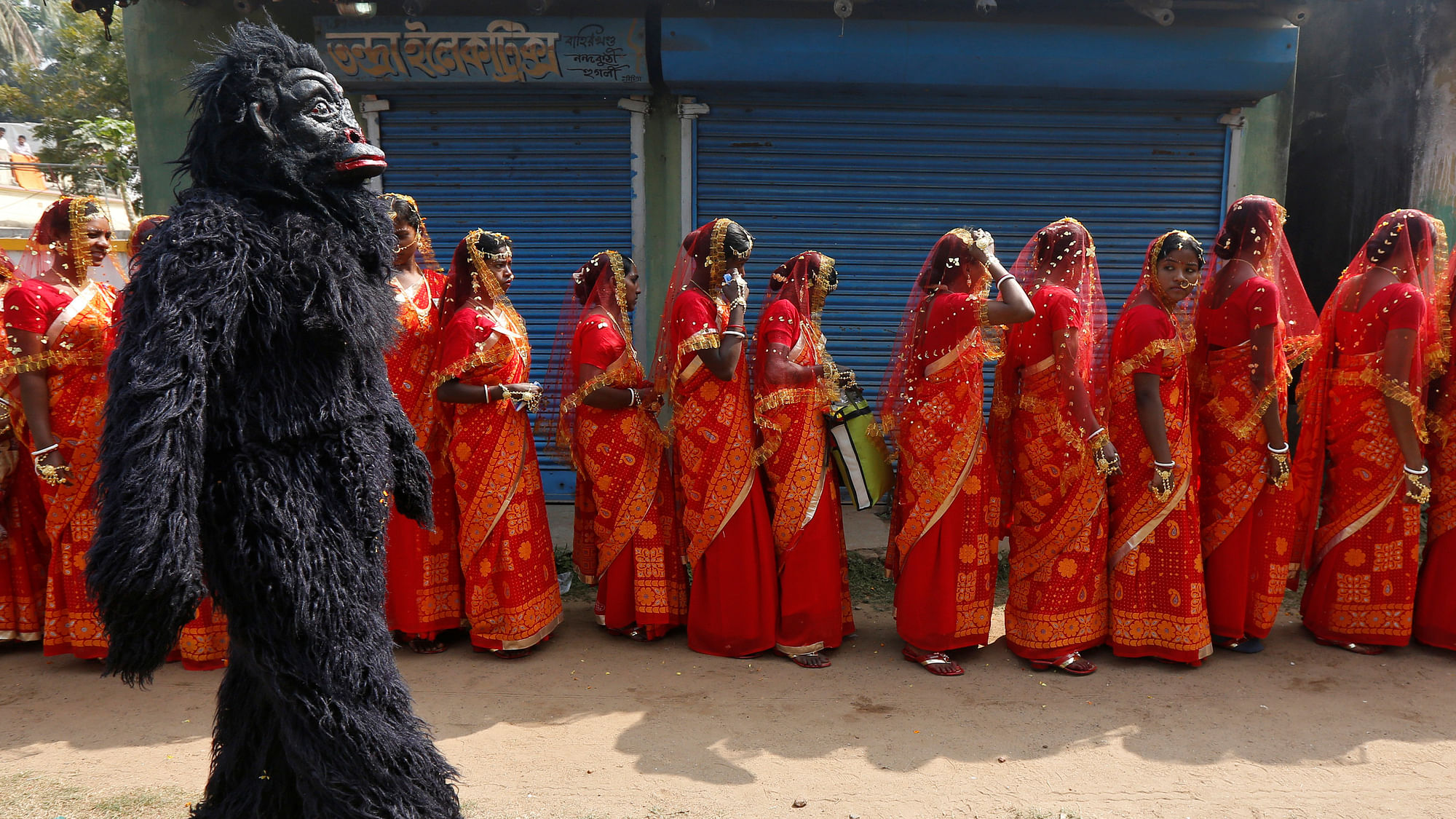 A performer dressed in a chimpanzee costume walks past brides as they arrive at a mass marriage ceremony in which, according to its organisers, 109 tribal, Muslim and Hindu couples from various villages across the state took their wedding vows, at Bahirkhand village, north of Kolkata. (Photo: Reuters/Rupak De Chowdhuri)