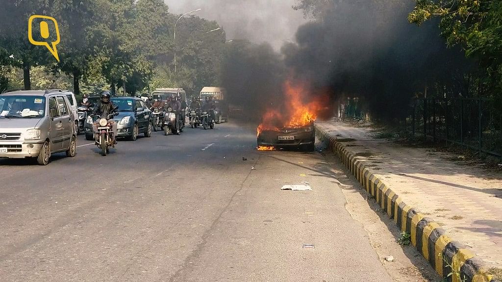 A car caught fire on the busy Dadri Main Road near Noida Sector 15A. (Photo: <b>The Quint</b>)