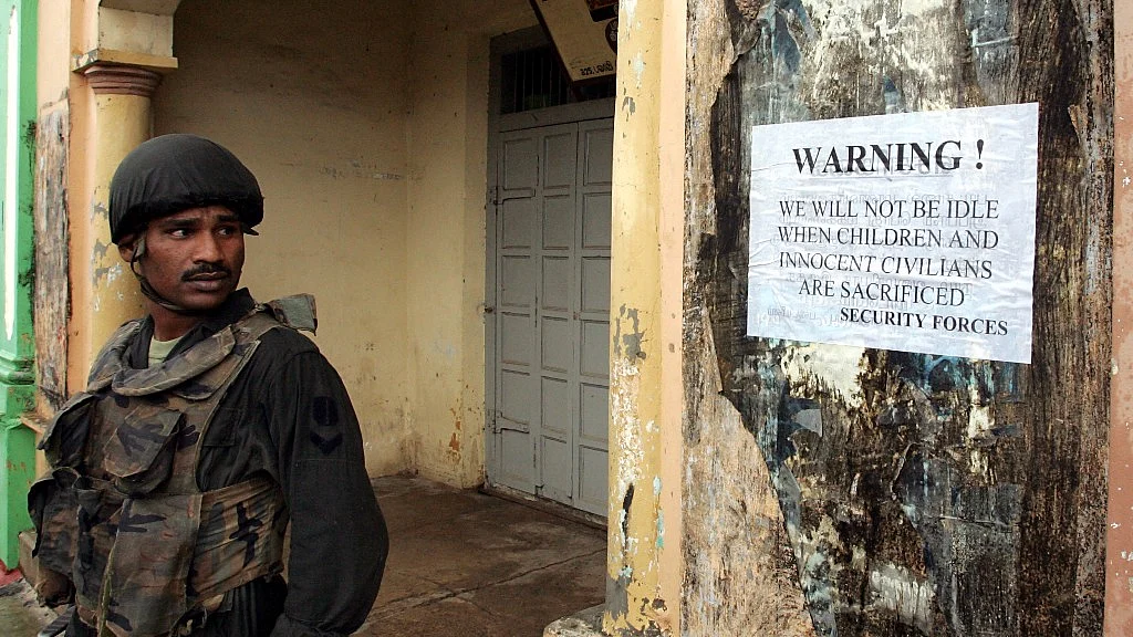 A Sri Lankan soldier stands by an army poster on the streets of Jaffna, northern Sri Lanka, 5 January 2006. (Photo: Reuters)