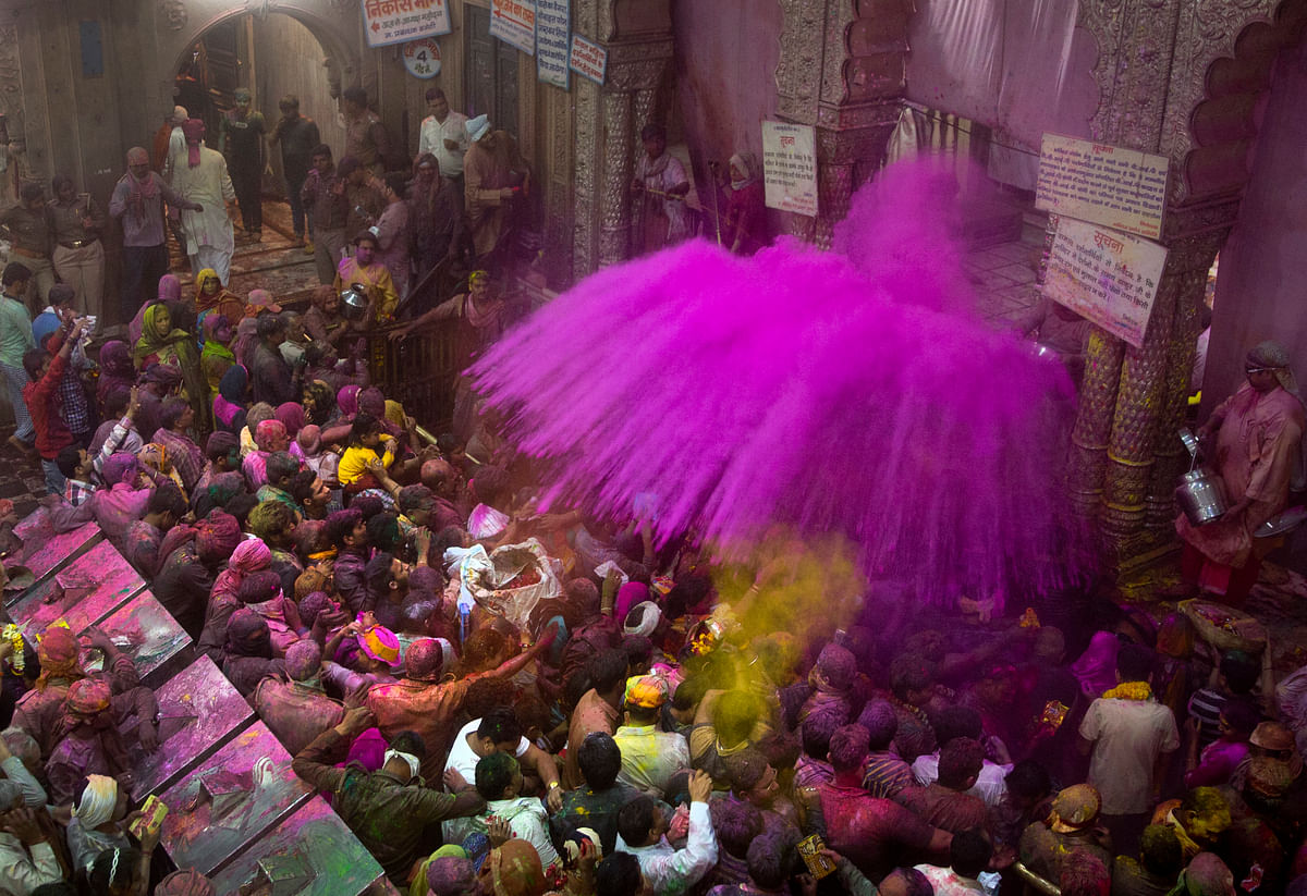 

Hindu priests throw color powders at the devotees inside Banke Bihari temple. (Photo: AP)