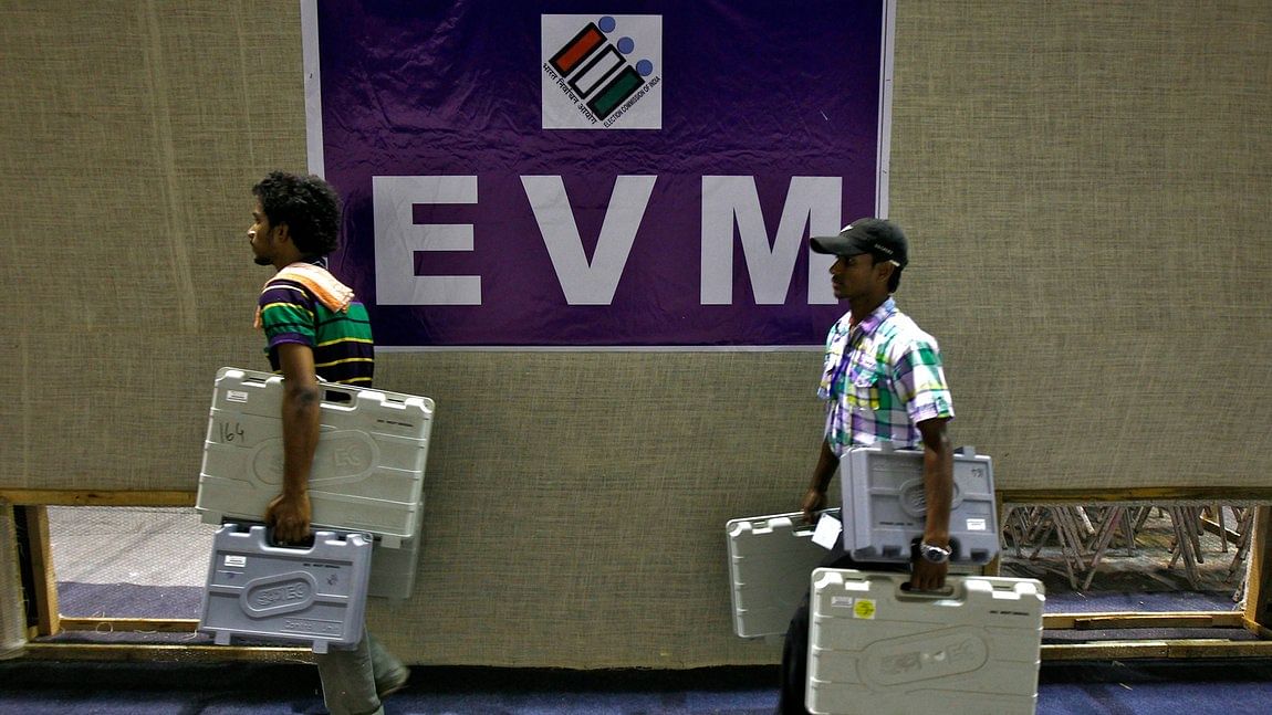 Election staff carry electronic voting machines (EVMs) after collecting them from a distribution centre. (Photo: Reuters)