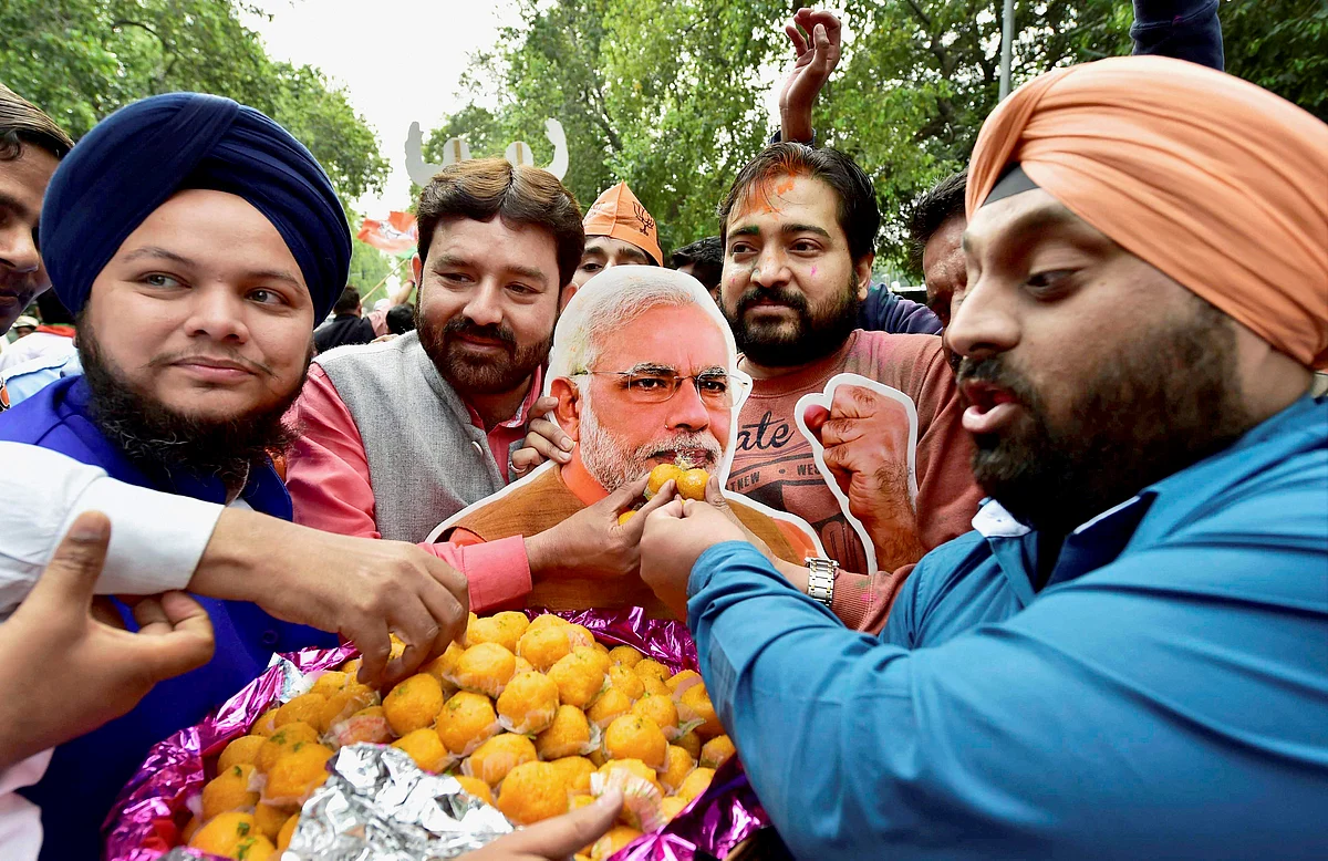 BJP supporters offer sweets to a cutout of PM Narendra Modi as they celebrate the party’s victory in the assembly elections. (Photo: PTI)