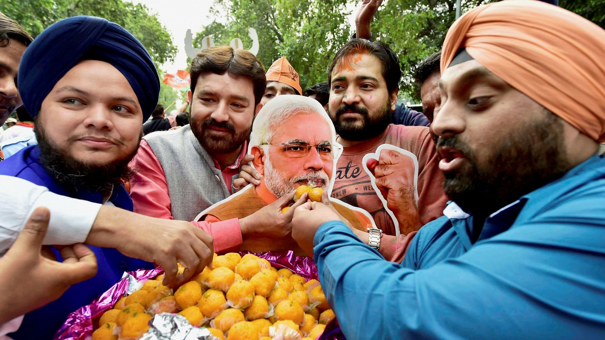 BJP supporters offer sweets to a cutout of PM Narendra Modi as they celebrate the party’s victory in the assembly elections. (Photo: PTI)