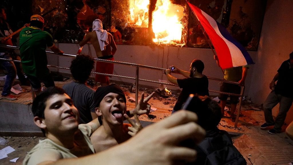 Men pose for a photo outside the Congress building in Paraguay during clashes between police and protesters over a proposed constitutional amendment that would allow the presidential re-election. (Photo: AP)  