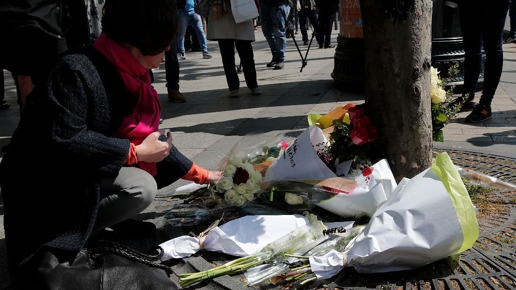 A woman lay flowers at the place where a police officer was killed Thursday on the Champs Elysees boulevard, Friday, April 21, 2017 in Paris. (Photo&nbsp;