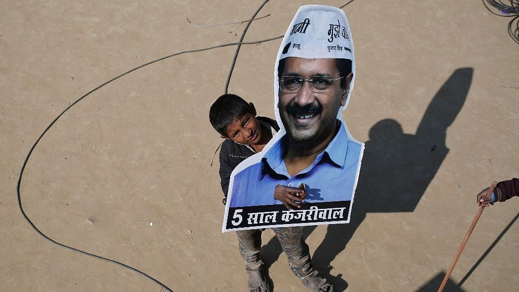 A boy looks on as he holds a portrait of Delhi Chief Minister Arvind Kejriwal. (Photo Courtesy: Reuters)