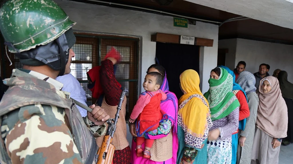 A soldier stands guard as women queue up to cast their votes during byelection for the Srinagar-Budgam parliamentary seat in Srinagar on 9 April 2017. (Photo: IANS)