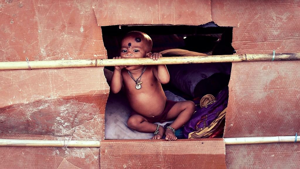 A child whose parents belong to the Rohingya community from Myanmar, looks out from a makeshift shelter in a camp in New Delhi, 13 September 2014. (Photo: Reuters)
