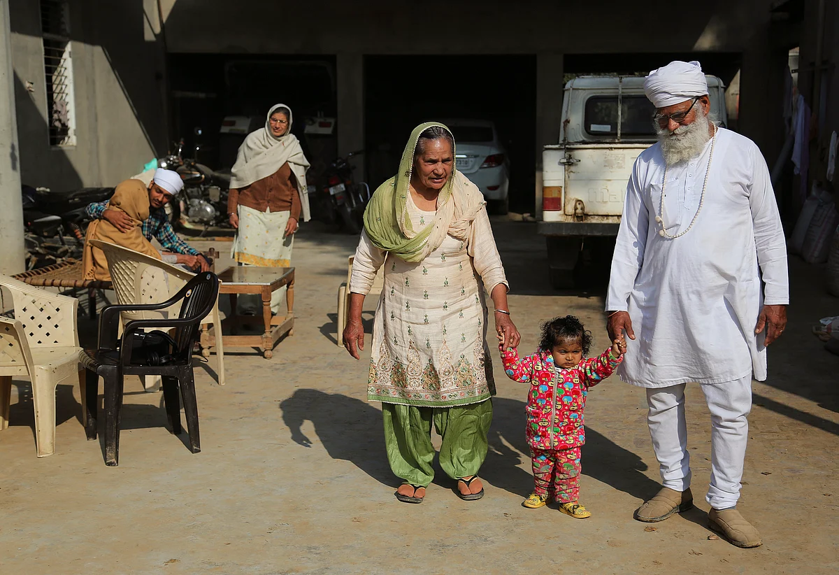 Manjeet Kaur, left, and her husband Gurdev Singh, right, walk with their daughter Gurjeet Kaur in the compound of their house in Ellenabad. (Photo: AP)