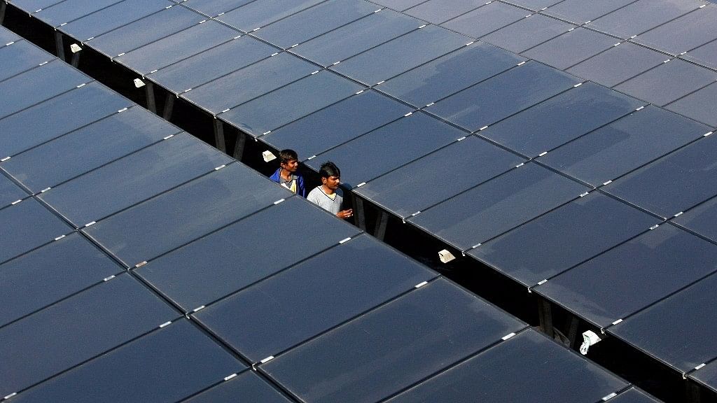 Workers walk between rows of solar photovoltaics, inside a solar power plant at Raisan village near Gandhinagar. (Photo: Reuters)