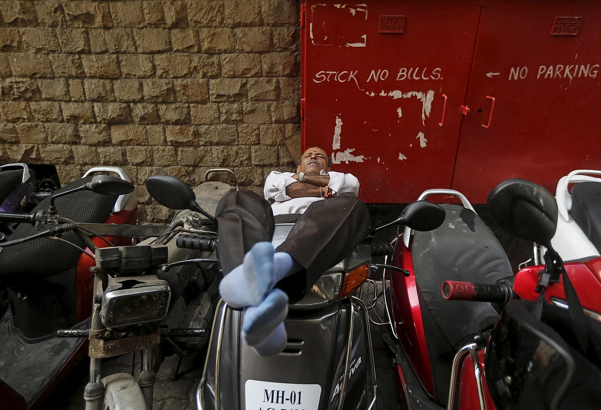 A man sleeps on a scooter at a parking lot in Mumbai. (Photo: Reuters)