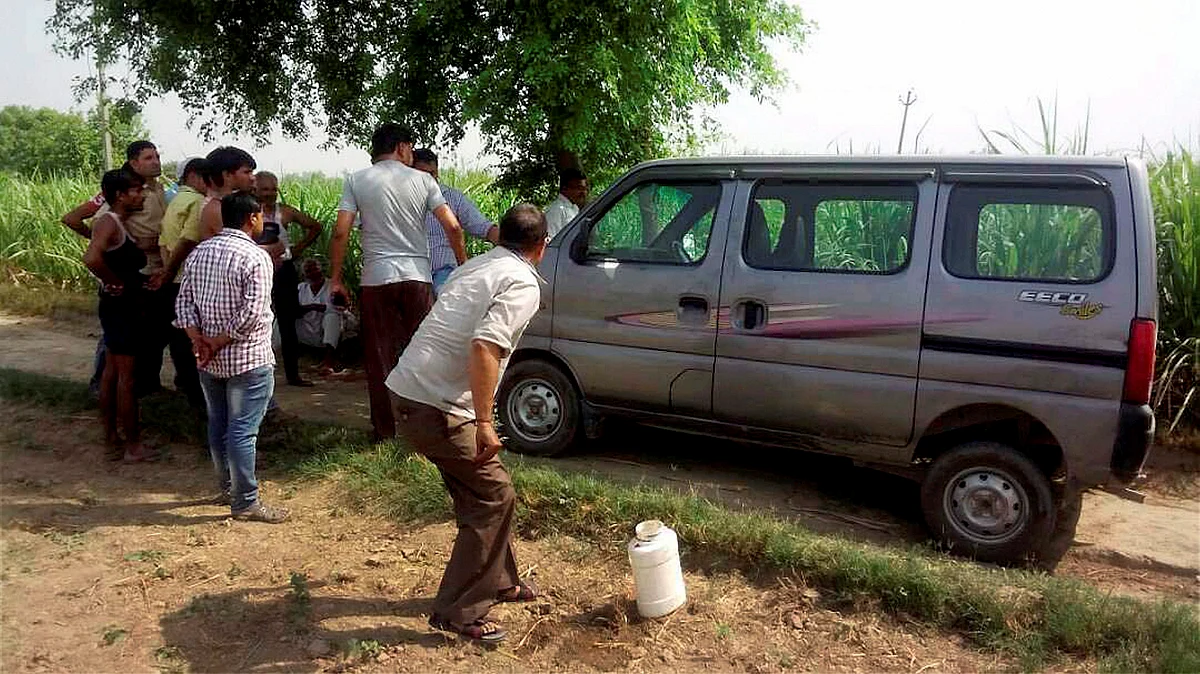 Villagers look on as police investigate near the vehicle, Maruti Suzuki Eeco, in which seven members of family along with a driver were travelling while being attacked. (Photo: PTI)