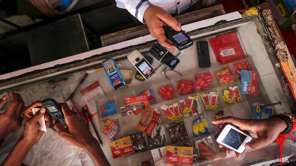  Customers wait to recharge their mobile phones as a vendor checks another device at a mobile phone store in the Dharavi slum area of Mumbai, India, on Tuesday, 12 August 2014. (Photo: Dhiraj Singh / Bloomberg)