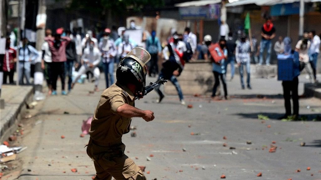 A Policeman in action against stone pelters during violent clashes which erupted following the killing of Slain Hizbul Mujahideen Commander Zakir Ahmad Bhat. (Photo: PTI)