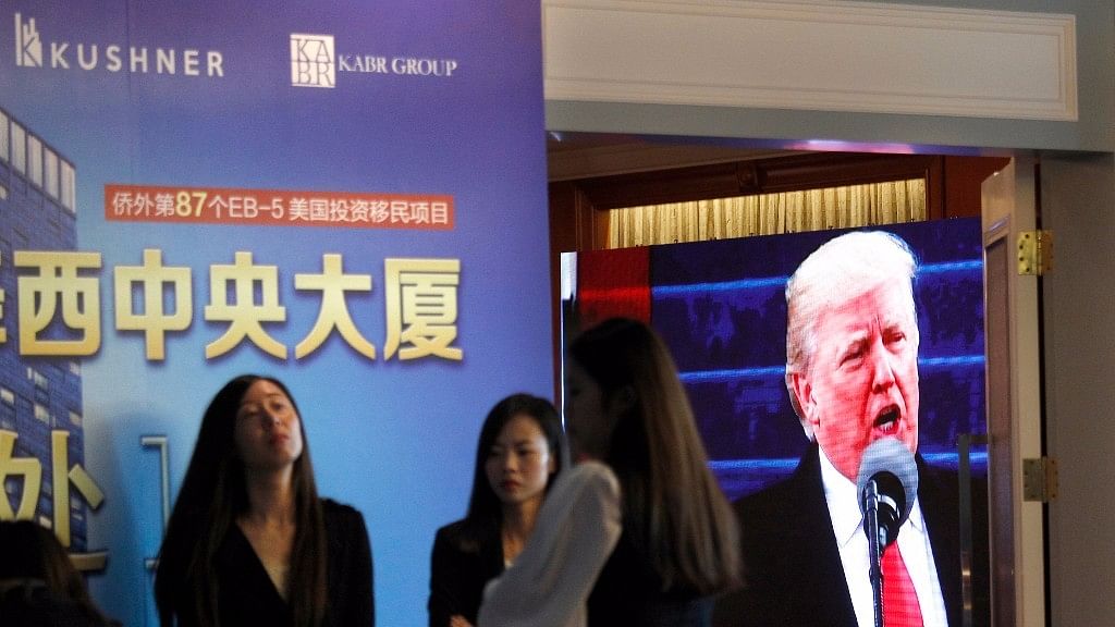 A projector screen shows a footage of US President Donald Trump as workers wait for investors at a reception desk during an event promoting EB-5 investment in a Kushner Companies development, at a hotel in Shanghai. (Photo: AP)