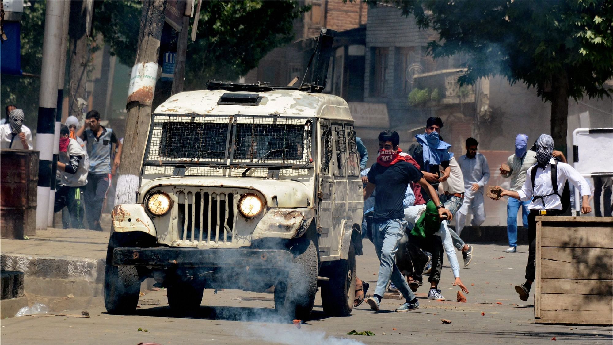 

A youth attacks a police vehicle amid tear smoke fired by police during violent clashes which erupted following the killing of Sabzar Ahmad Bhat. (Photo: PTI)