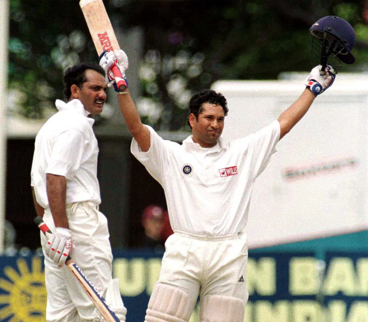 Sachin Tendulkar raises his arms to the crowd after scoring a century against New Zealand as his captain Mohammad Azharuddin looks on, during day four of the second cricket test at the Basin Reserve on 29 December. (Photo: Reuters)