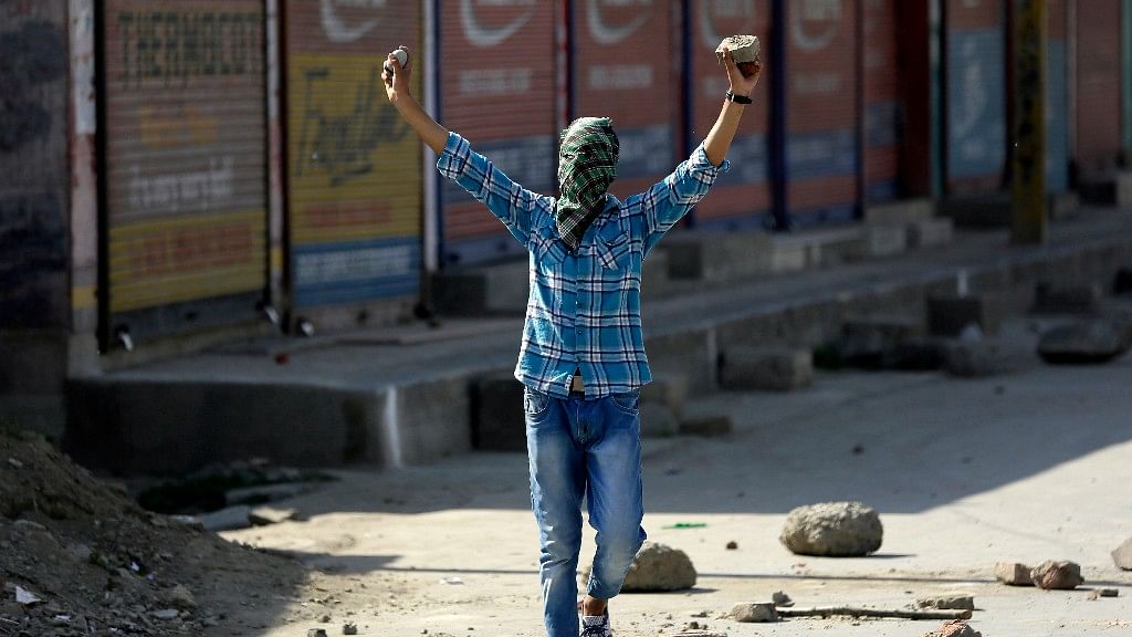 

A masked  protester shouts freedom slogans before throwing a rock at policemen in Srinagar, 27 May, 2017. (Photo: AP)