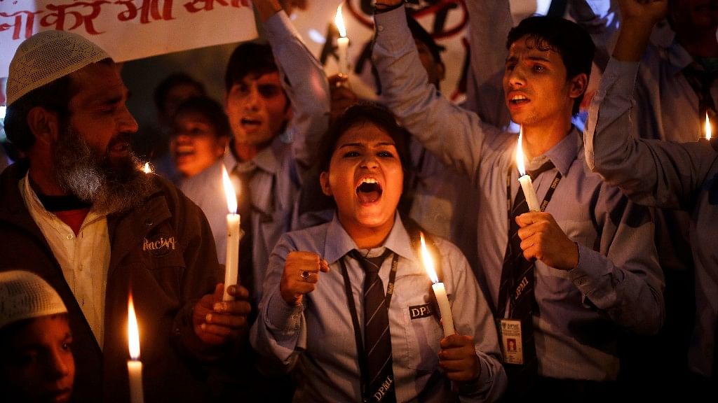 Schoolchildren shout slogans as they hold candles during a candle light vigil to mark the first anniversary of the Delhi gangrape. (Photo: Reuters)