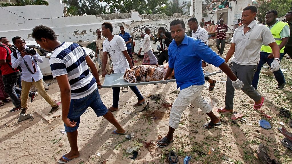 Somali men carry away the body of a civilian who was killed in the militant attack. (Photo: AP)