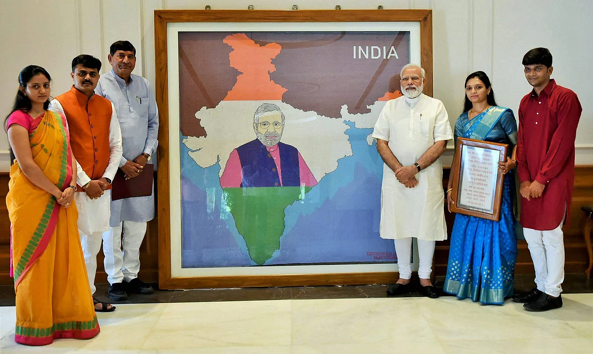 Khushboo Akash Davda presents her artwork to PM Modi in New Delhi. It took over five lakh pearls to make the piece. (Photo: PTI)