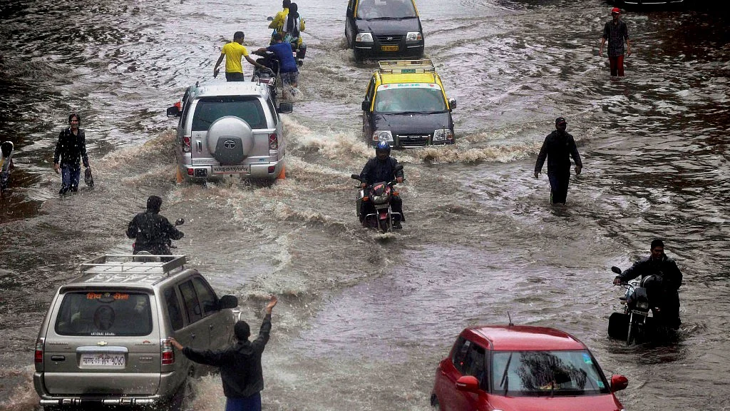 People wade through a water logged road after heavy rains in Mumbai (Photo: PTI)