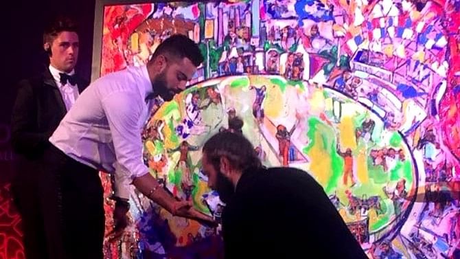 Virat Kohli ready to create a hand print on the painting, with artist Sacha Jafri applying paint on his hand.&nbsp;