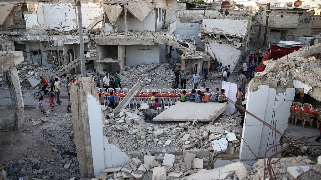 People gather amidst damaged buildings during Iftar, organised by Adaleh Foundation, in the rebel-held besieged Douma neighborhood of Damascus, Syria.  (Photo: Reuters/Bassam Khabieh)