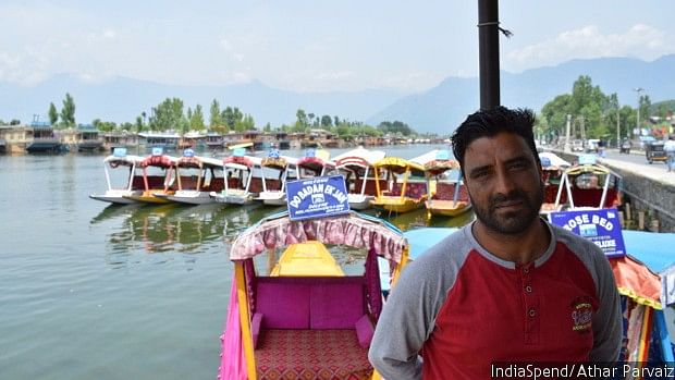 Rizwan Ahmad Bhat, standing near his Shikara (boat) at Dal Lake in Srinagar. (Photo courtesy: IndiaSpend/Athar Parvaiz)