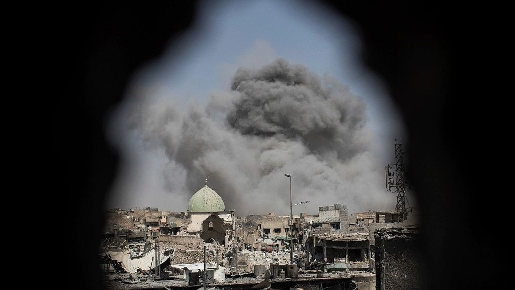 A bomb explodes behind the al-Nuri mosque complex, as seen through a hole in the wall of a house, as Iraqi Special Forces move toward ISIS militant positions in the Old City of Mosul, Iraq, Thursday.&nbsp;