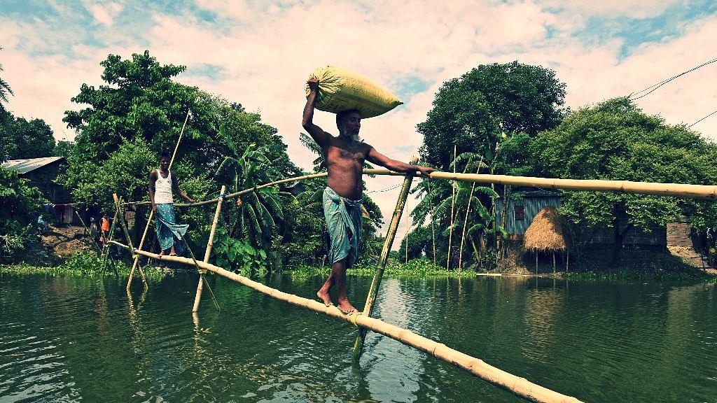 Villagers use a makeshift bamboo bridge to move across flooded areas of Morigaon district in the northeastern state of Assam. (Photo: Reuters)