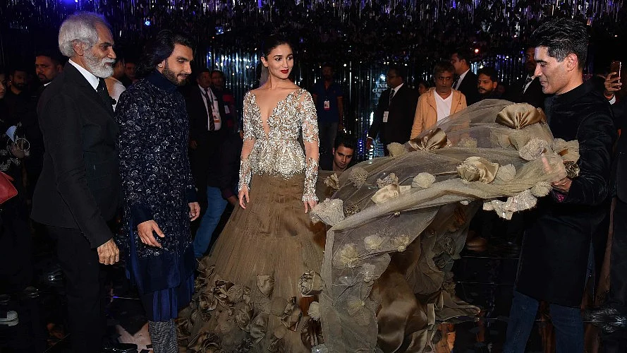 Manish Malhotra arranges Alia Bhatt’s dress while Ranveer looks on.