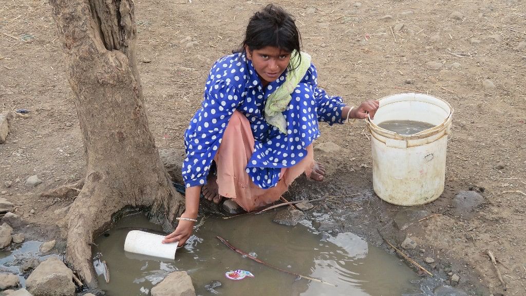 

A young woman fills her bucket with dirty water fearing that the handpump might give out anytime.